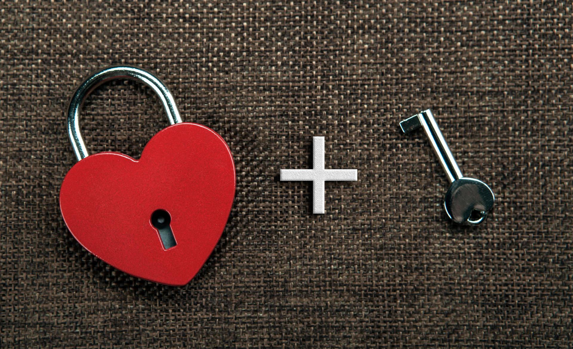 heart shaped padlock with a key on gray linen top view