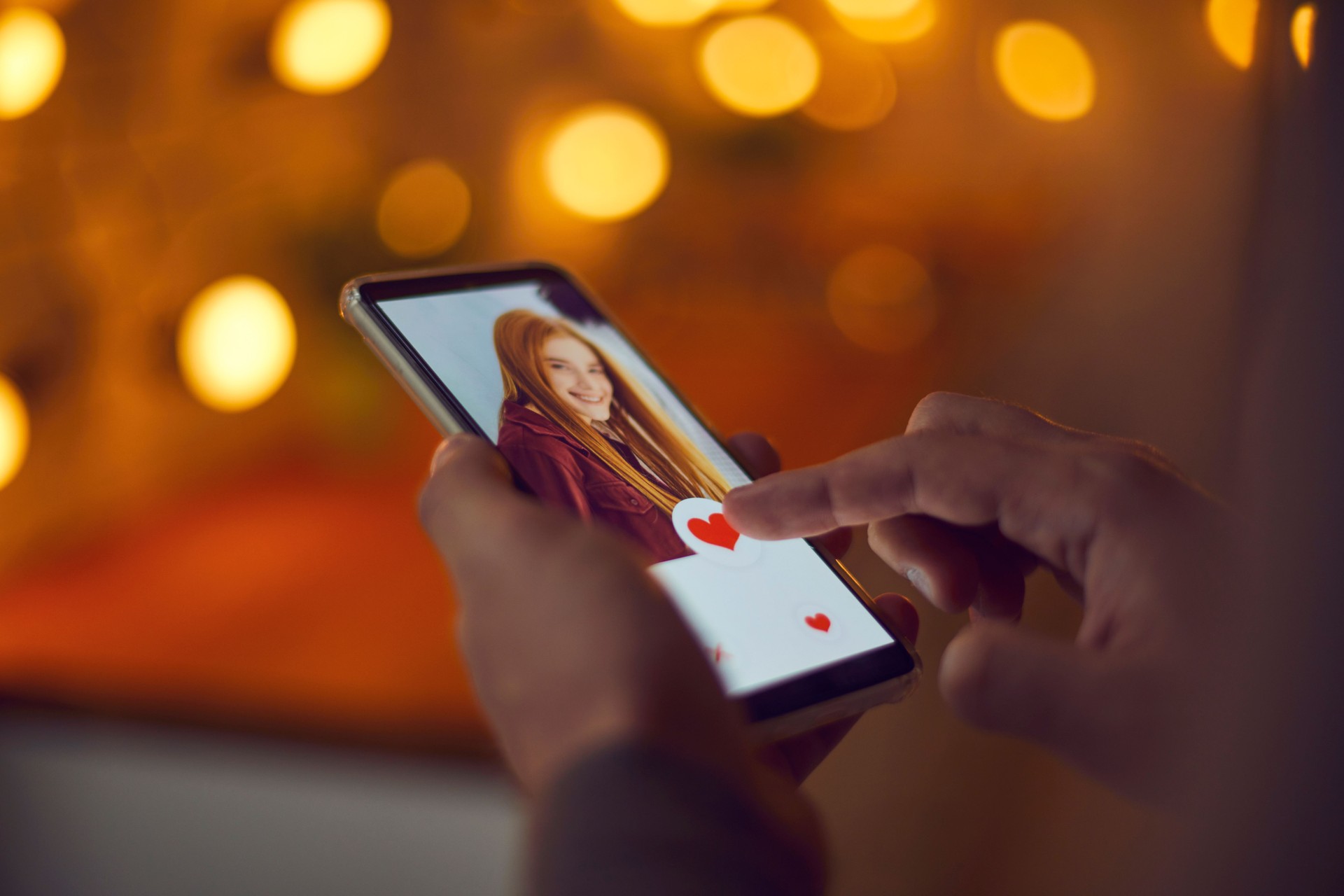 Man holding smartphone and pressing like below attractive young woman's profile photo