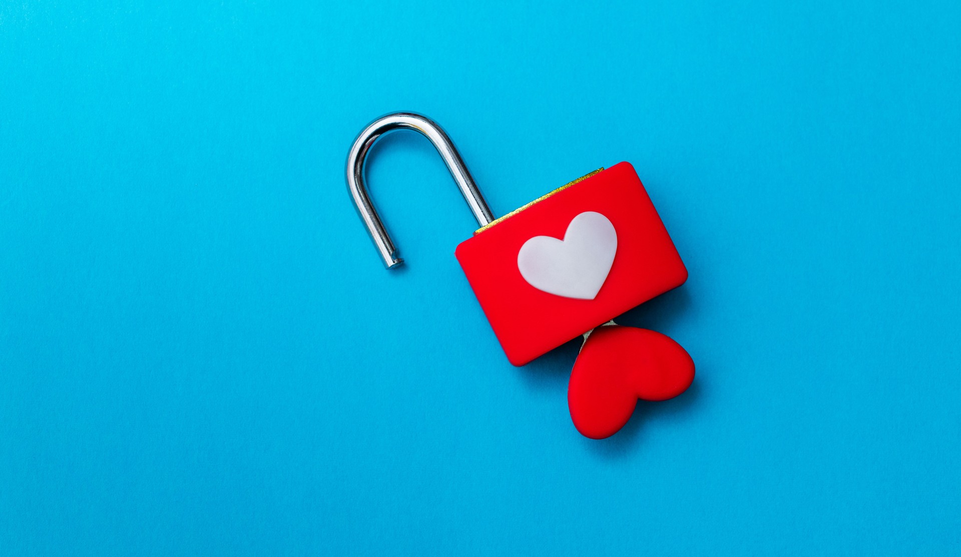 Padlock with heart shape key on blue background